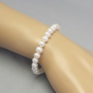 May include: A white pearl bracelet with a simple  and elegant design.