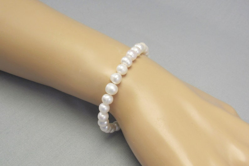May include: A white pearl bracelet with a simple  and elegant design.