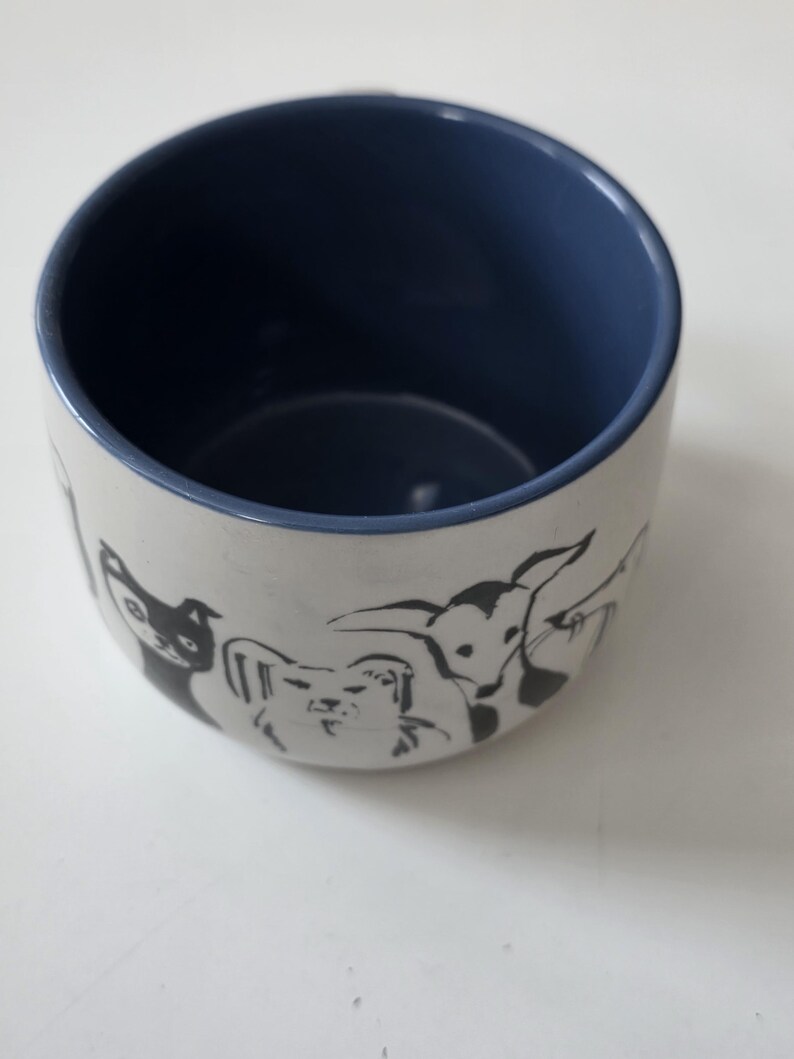 May include: A set of three ceramic canisters with lids. The canisters are white with a textured surface and feature a black geometric pattern. The lids are black. The canisters are of varying sizes.