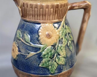 MAJOLICA POTTERY Pitcher With Butterfly Spout, Floral and Foliate Design to Body, and Basket Weave Bottom. 7 Inches Tall