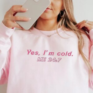 May include: A pink sweatshirt with the text "Yes, I'm cold. ME 24/7" in pink.
