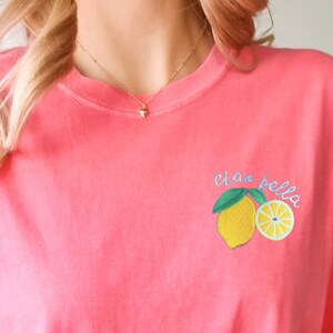 May include: A pink t-shirt with a lemon graphic and the text "Ciao Bella" embroidered on the front.