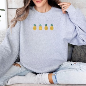 May include: A gray sweatshirt with a row of four embroidered yellow pineapples on the front.