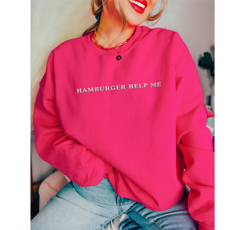 May include: A bright pink sweatshirt with the text "Hamburger Help Me" embroidered in silver on the front.
