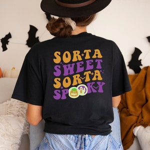Pode incluir: Camiseta preta com um gr&aacute;fico de estilo retro que diz "Sorta Sweet Sorta Spooky" com uma ilustra&ccedil;&atilde;o de ab&oacute;bora e fantasma.