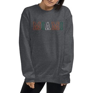 May include: A dark gray sweatshirt with the word "MIAMI" printed in white with orange and green outlines.