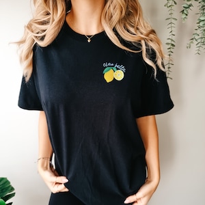 May include: Black t-shirt with a lemon graphic and the text "ciao bella" in blue.