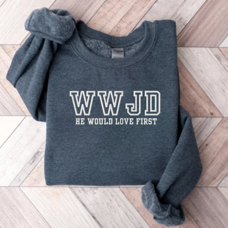 May include: A dark gray sweatshirt with the text "WWJD HE WOULD LOVE FIRST" in white.