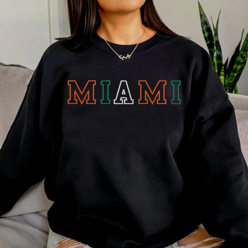 May include: Black sweatshirt with the word "MIAMI" in orange, green, and white outlined letters.