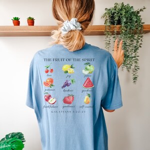 May include: A light blue t-shirt with a graphic of fruit and the text "THE FRUIT OF THE SPIRIT" and "GALATIANS 5:22-23".