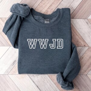May include: A dark gray sweatshirt with the text "WWJD" in white outlined letters.