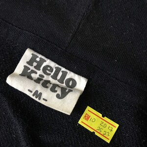 May include: Black Hello Kitty hoodie with a white tag that says "Hello Kitty -M-". A yellow price tag is attached to the hoodie that says "RM 10 20 17 25 23".