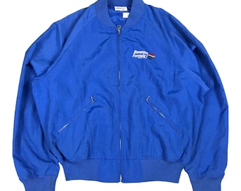 May include: A blue nylon bomber jacket with a zipper closure and a Benetton Formula 1 logo embroidered on the chest.