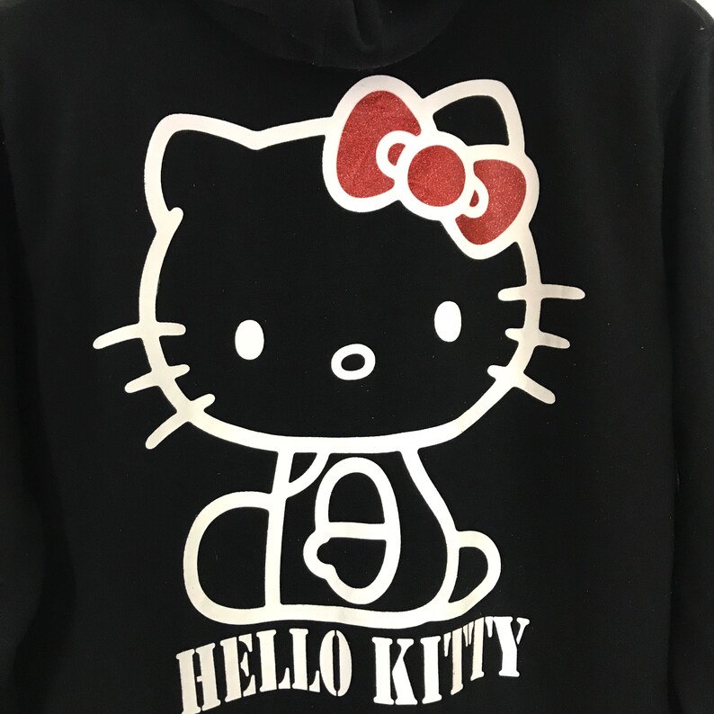 May include: Black hoodie with a white outline of Hello Kitty wearing a red bow. The text "HELLO KITTY" is printed in white below the image.