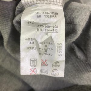 May include: Close-up of a clothing tag with Japanese text and washing symbols. The tag includes the product code STDHA13-C125R and size 3L. Fabric composition is listed as 65% polyester, 35% cotton, 62% polyester, 33% cotton, and 5% polyurethane.
