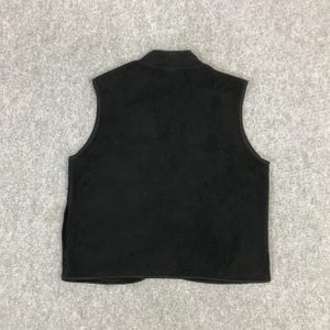 以下が含まれることがあります： スタンドカラーの黒いフリースベスト。袖なしのベストは、フロントにフルジッパーと両サイドにポケットが付いています。ベストは柔らかく、質感のある素材で作られています。