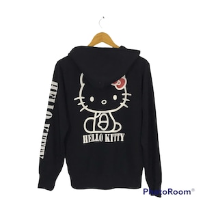May include: Black hooded sweatshirt with a white Hello Kitty graphic on the back and the words "Hello Kitty" printed below. The left sleeve has the words "Hello Kitty" printed vertically in white.