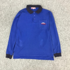 May include: A long-sleeved blue polo shirt with a black collar and cuffs. The shirt features a small pocket on the chest with the text "TOYOTA MOTOR SPORTS TRD" in red and white. The shirt has a three-button placket.