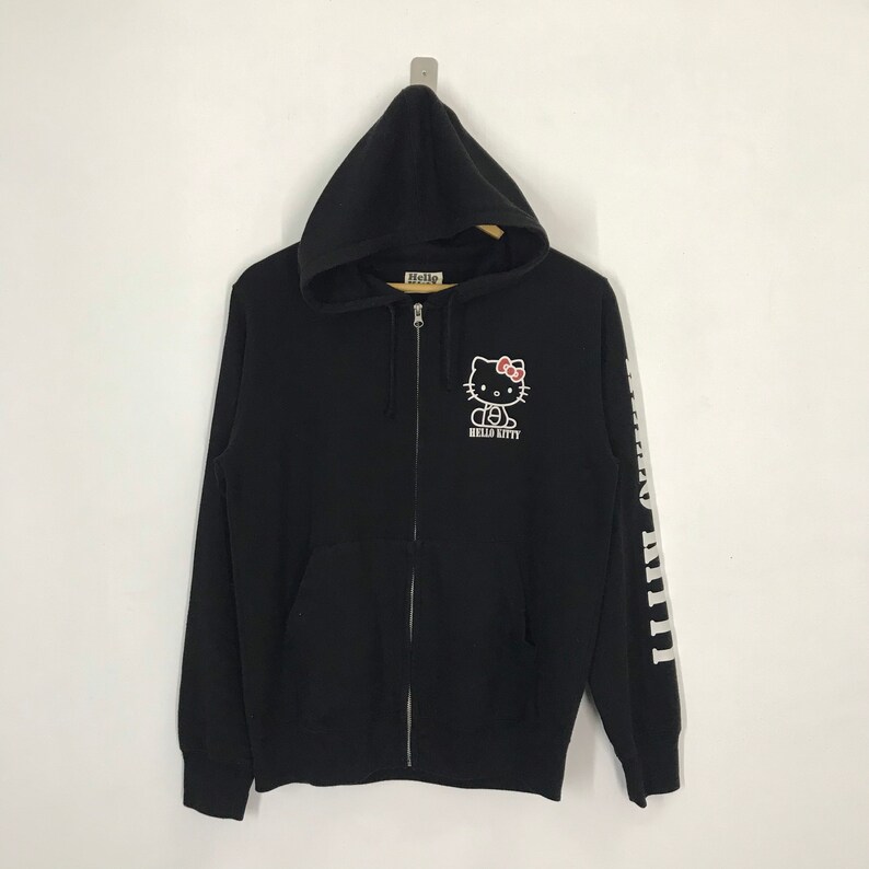 May include: Black zip-up hoodie with a Hello Kitty graphic on the front and "Hello Kitty" text on the left sleeve.