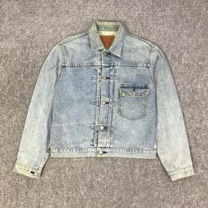 Op de afbeelding: Lichtblauwe spijkerjas met een knoopsluiting, twee borstzakken en een klassieke kraag. De jas heeft een vervaagde wassing en een vintage uitstraling. Het Levi's-merkteken is zichtbaar aan de binnenkant van de kraag.