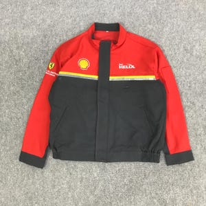 May include: Red and black jacket with the Shell and Helix logos. The jacket has a yellow stripe across the chest and a Ferrari logo on the left sleeve. The jacket has a zipper closure and two front pockets.