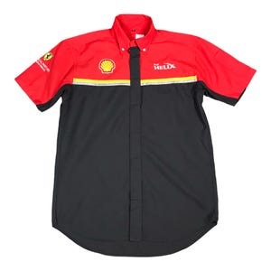 以下が含まれることがあります： 赤と黒の半袖ボタンアップシャツ。胸には黄色とシルバーのストライプがあり、前面にはShellのロゴと「HELIX」の文字がプリントされています。左袖にはフェラーリのロゴがあります。