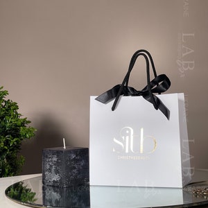Bolsa de embalaje de producto personalizada con logo dorado / bolsa de regalo blanca con lazo de raso para cuidado de la piel y accesorios / bolsa del día de la boda 50 piezas
