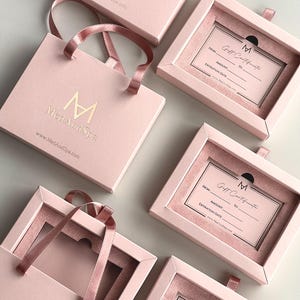May include: Pink gift boxes and bags with the "MedAndSpa" logo and website address. The boxes contain gift certificates with fill-in fields for "From," "To," "Amount," and "Expiration Date."