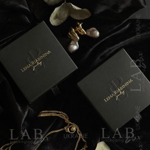 May include: Two black jewelry boxes with gold lettering that reads "LENA RIABININA jewelry" on a black velvet background. The boxes are labeled "LABox packaging" and "UKRAINE".