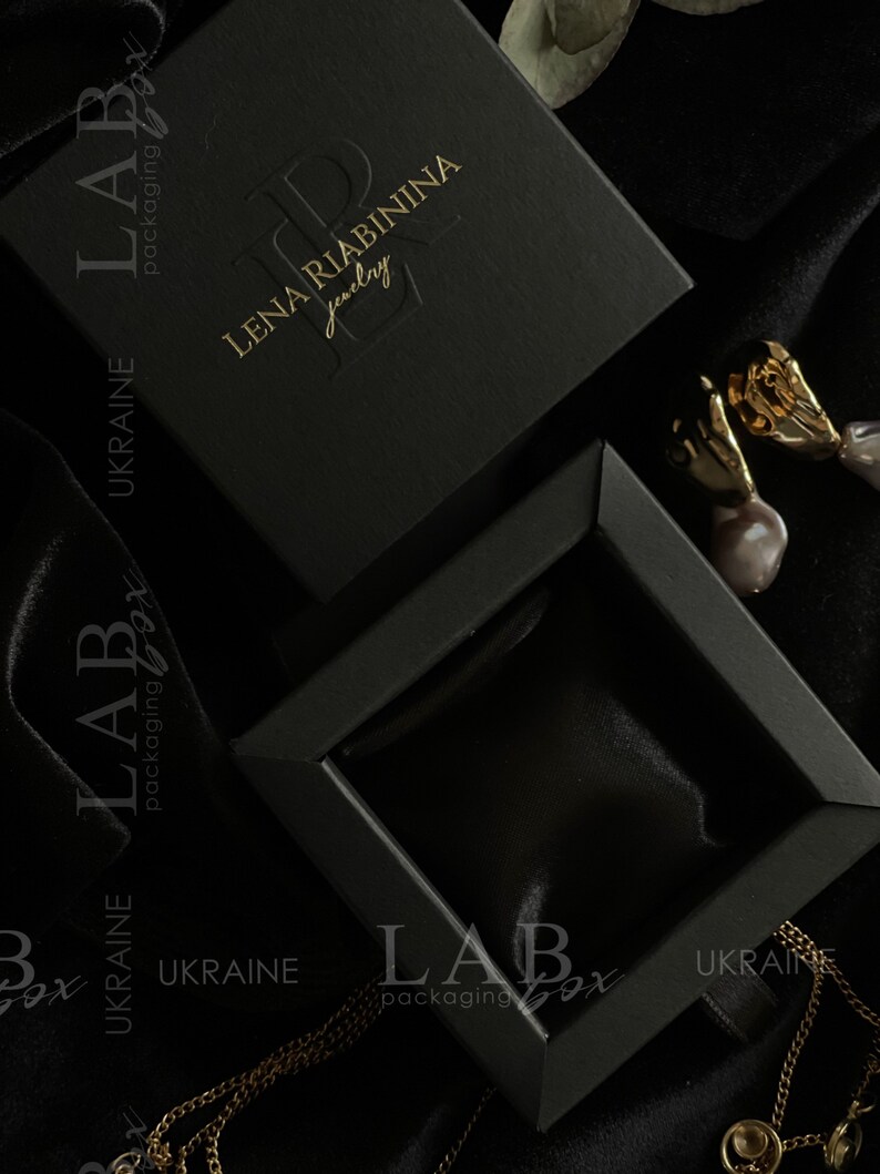 May include: Black jewelry box with a gold embossed logo that reads "LENA RIABININA jewelry". The box is open and the inside is lined with black velvet.
