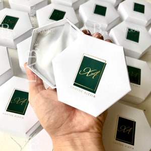 May include: White hexagonal gift boxes with a green and gold logo that says "Xanthe Alexia" and the initials "XA" in gold script.