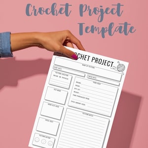 May include: A white Crochet Project Template held by a hand with a pink nail polish. The template has sections for pattern details, yarn information, and notes. The background is a solid pink color, with the words "Crochet Project Template" in a script font.