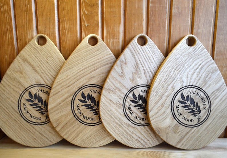 May include: Four wooden cutting boards in a teardrop shape with a handle. Each board has a black circle with a leaf design and the text "VALBURDEN MAGIC WOOD".