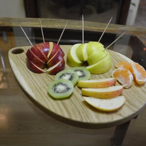 May include: A wooden serving board with a variety of fruit slices, including red apple, green apple, kiwi, and orange. The fruit is arranged in a circular pattern on the board.