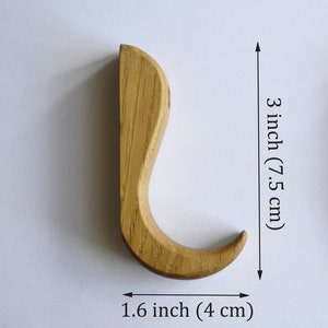 May include: A wooden hook with a curved design, measuring 3 inches tall and 1.6 inches wide.