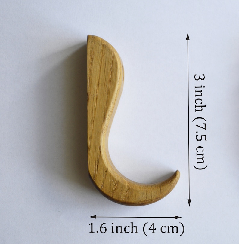 May include: A wooden hook with a curved design, measuring 3 inches tall and 1.6 inches wide.