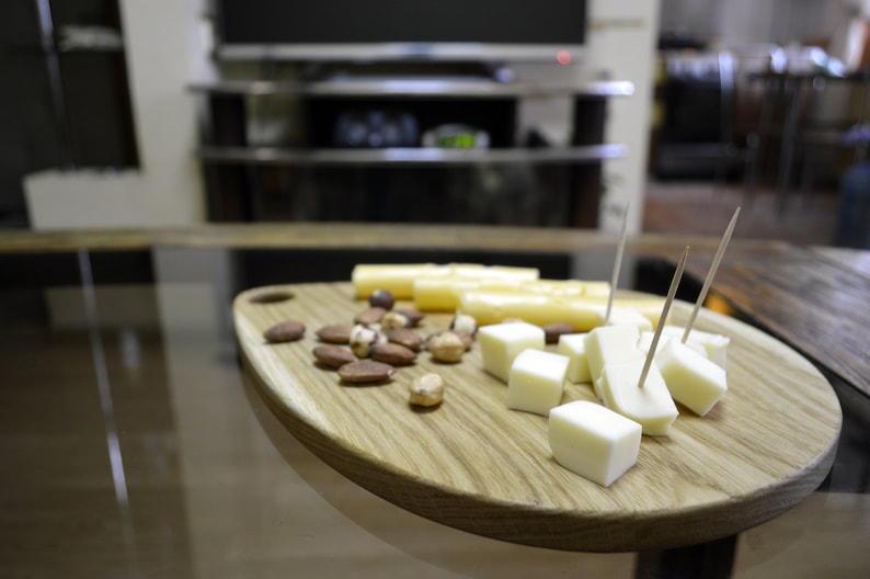 May include: A wooden serving board with a variety of snacks, including cheese cubes, breadsticks, and nuts.