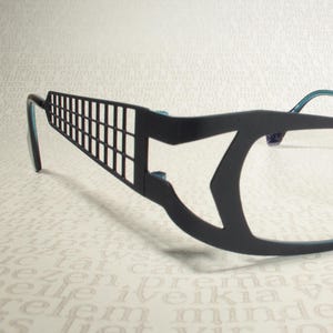 Peut inclure: Lunettes noires et bleu sarcelle avec un design géométrique sur la monture.