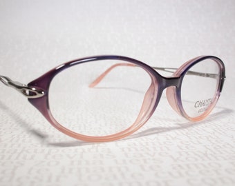 May include: Purple and pink oval-shaped eyeglasses with silver accents. The brand name "CHANTAL" is printed on the right temple.