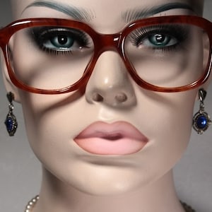 Könnte beinhalten: Nahaufnahme eines Mannequins mit Schildpattbrille und blauen Edelsteinohrringen.