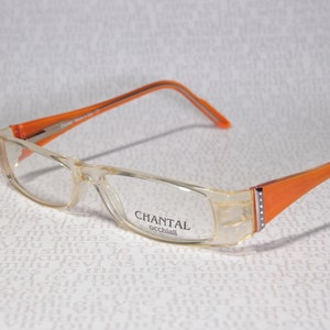 May include: Clear orange framed glasses with the brand name "CHANTAL occhiali" printed on the right lens.