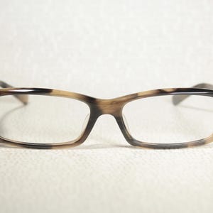 May include: Tortoiseshell eyeglasses with a brown and black pattern. The glasses have a rectangular frame and clear lenses.