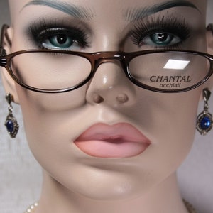 May include: A brown plastic frame with clear lenses and the text "CHANTAL occhiali" on the right lens. The glasses are worn by a mannequin with a neutral expression and blue earrings.