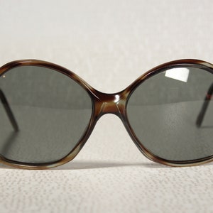 May include: A pair of brown tortoise shell oval sunglasses with dark gray lenses.