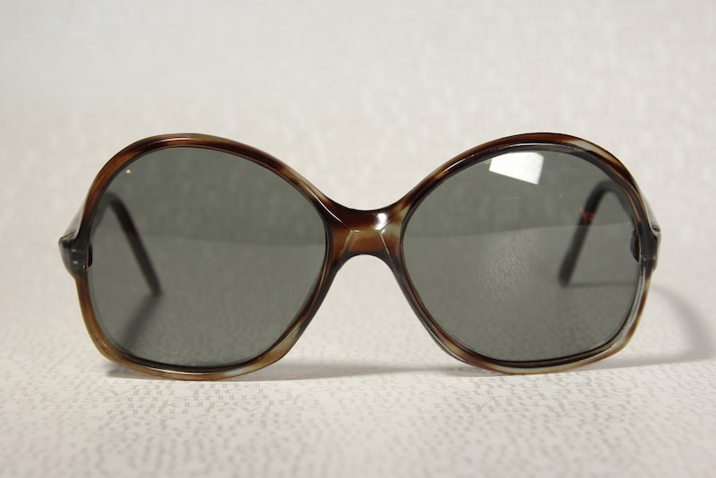 May include: A pair of brown tortoise shell oval sunglasses with dark gray lenses.