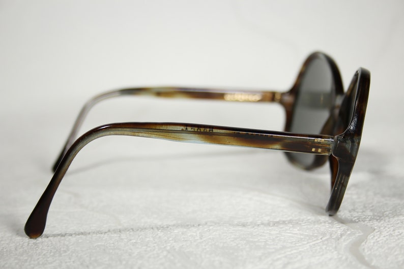 May include: Brown tortoiseshell sunglasses with round lenses and a thin metal bar across the bridge.