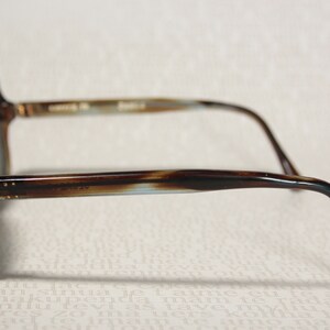 May include: Brown and blue tortoiseshell sunglasses with a rounded frame and thin arms.