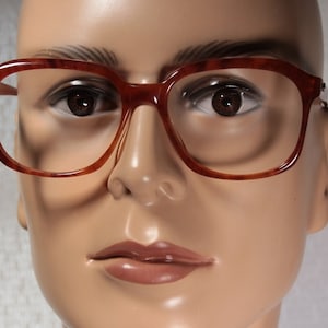 Peut inclure: Gros plan d'un mannequin portant des lunettes de vue en écaille de tortue avec une monture marron.