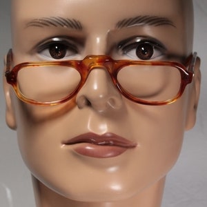 Può includere: Primo piano di un manichino che indossa occhiali tartarugati con montatura marrone.