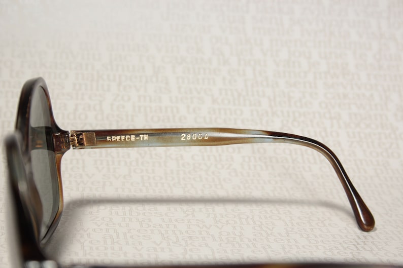May include: Brown tortoise shell sunglasses with brown lenses. The sunglasses have a gold metal hinge and the text "EDFFCE-TH 28004" is printed on the arm.
